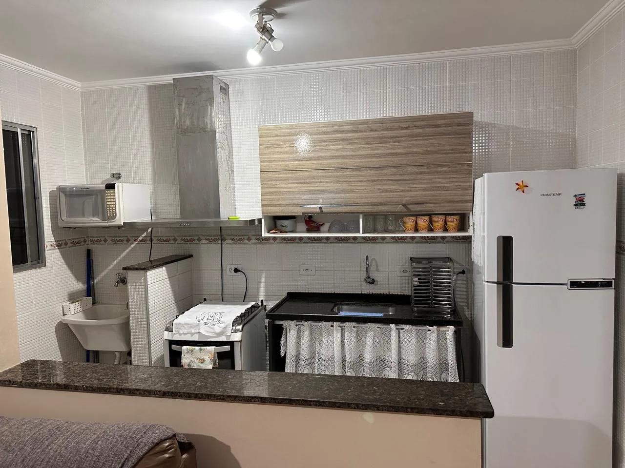Cozinha equipada com fogão, geladeira, micro-ondas e utensílios