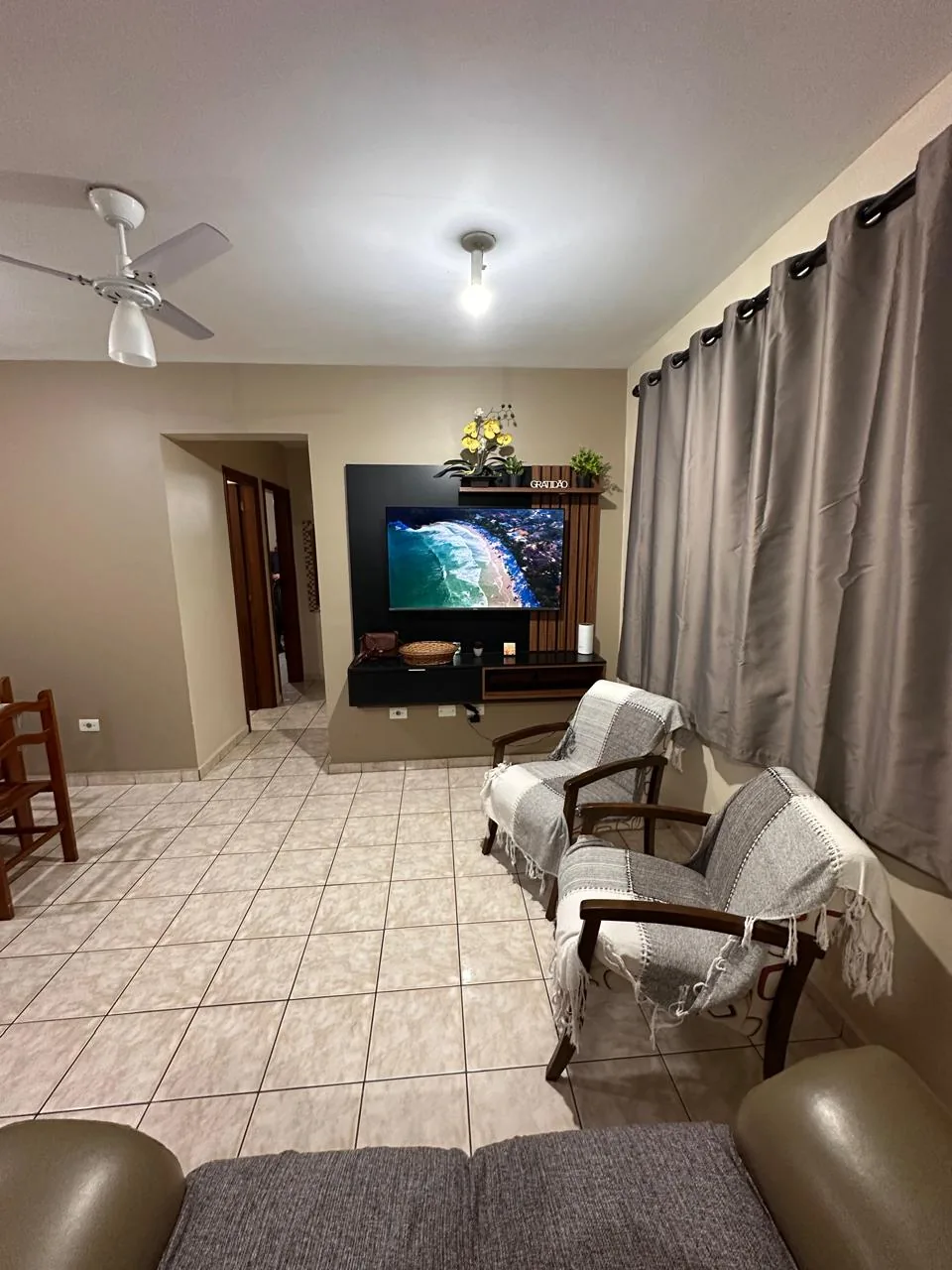 Segundo ângulo da sala mostrando o espaço de circulação, a TV e as poltronas